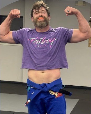 Chris Lemmel flexing on the mats in his blue gi pants and blue belt